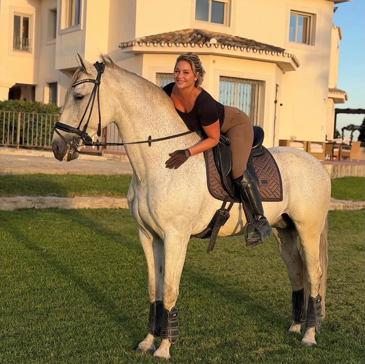 Smiling rider sharing a relaxed moment with a grey horse